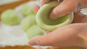 將均分的艾草面團(tuán)搓成圓，挖一個(gè)窩，放入餡心，再搓成圓。