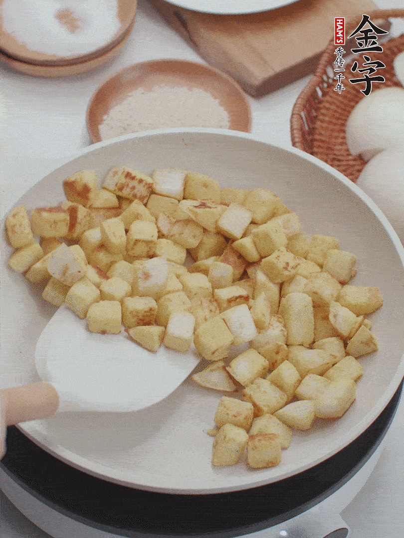 起鍋熱油，倒入饅頭丁，小火煎至蛋液凝固定型再翻面，饅頭丁部煎至金黃時盛起待用。